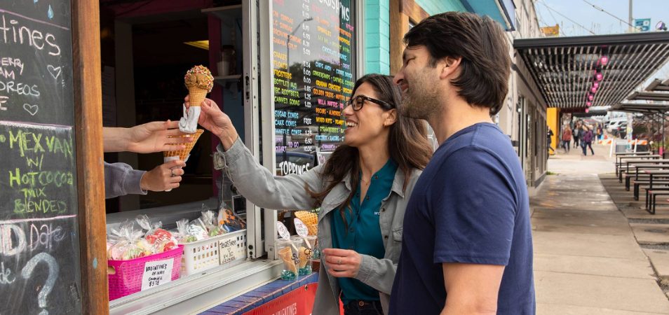 A man and woman reach for an ice cream cone from a food truck in Austin, Texas.