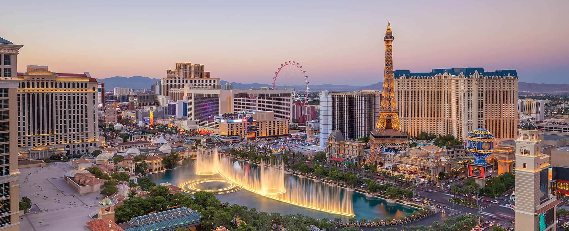 The Fountains at Bellagio and the Las Vegas Strip, lit up at sunset.