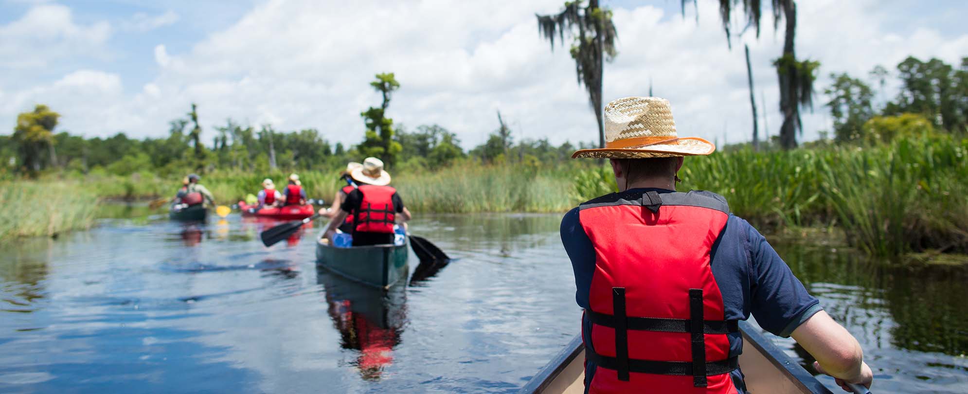 A group wearing life vests canoeing on a swamp tour in New Orleans