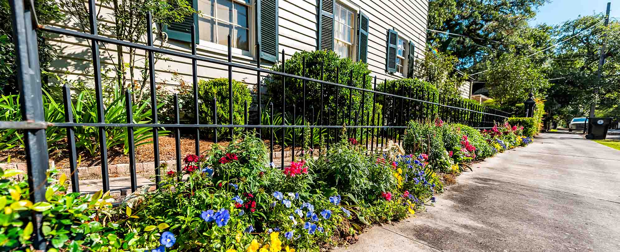 An iron fence surrounded by flowers in the New Orleans garden district.