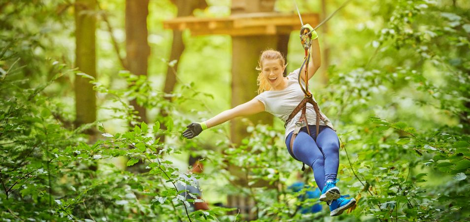 A woman smiles and holds her arm out while zip lining in Orlando, Florida.