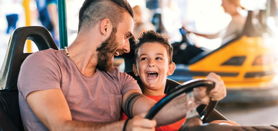 A father and son laugh as they drive bumper cars at an Orlando theme park