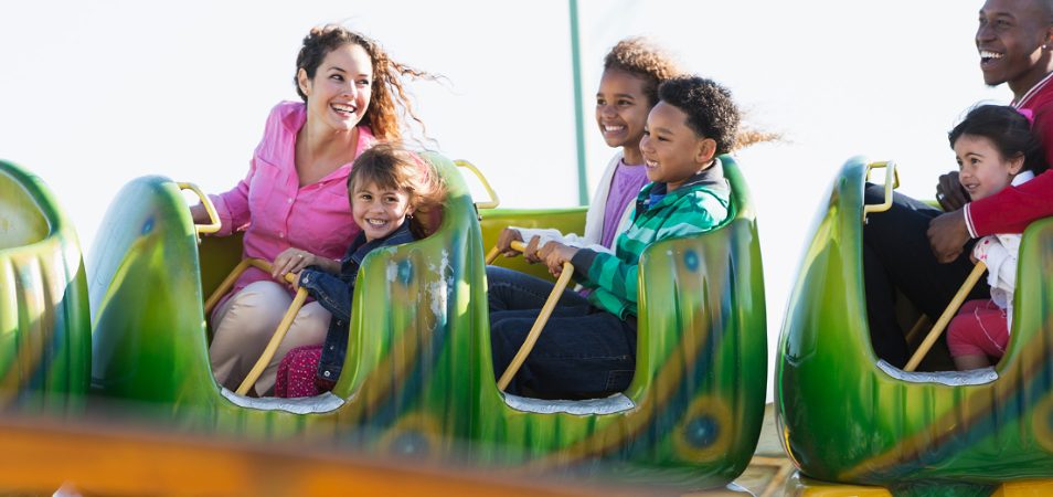 Kids and adults riding a children's rollercoaster at one of the Orlando theme parks.
