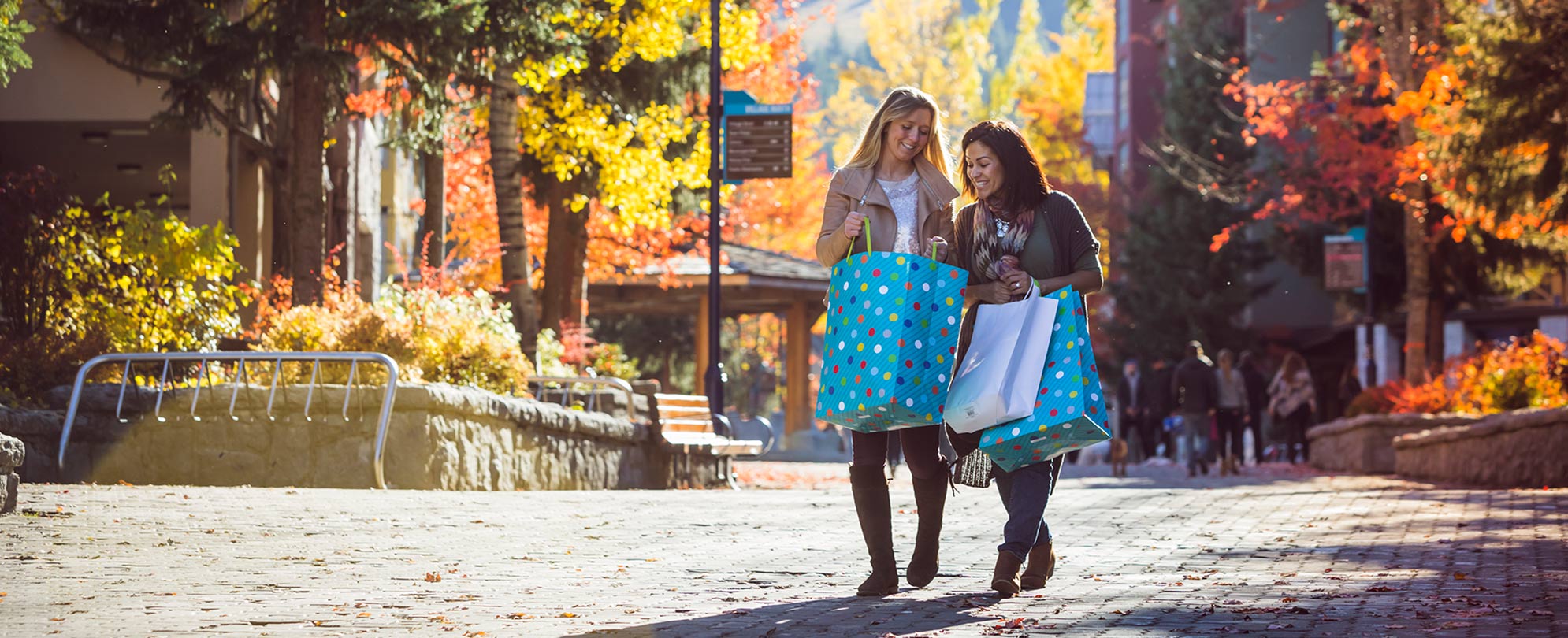 Two female friends carrying large shopping bags while shopping in Whistler Village.