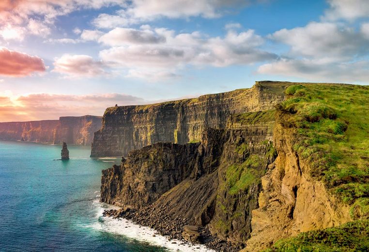 A man standing with his dog on the Cliffs of Moher in Ireland.