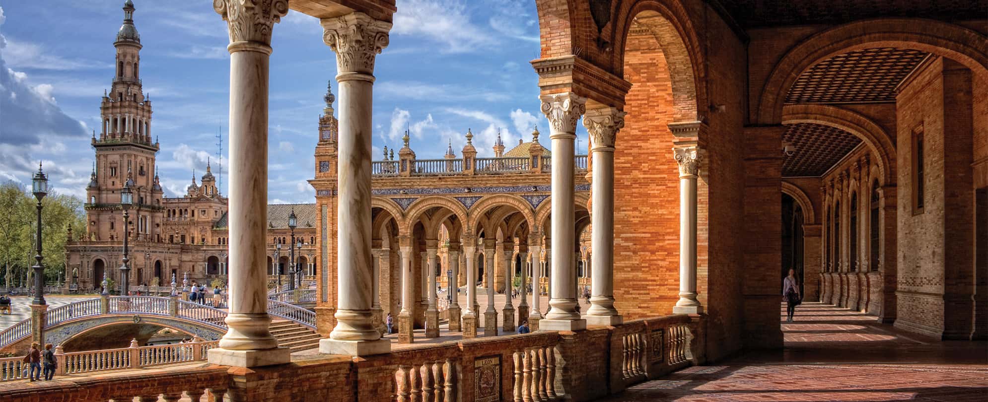 Marble columns, tall tower, and red stone architecture at the Plaza De Espana in Madrid, Spain.