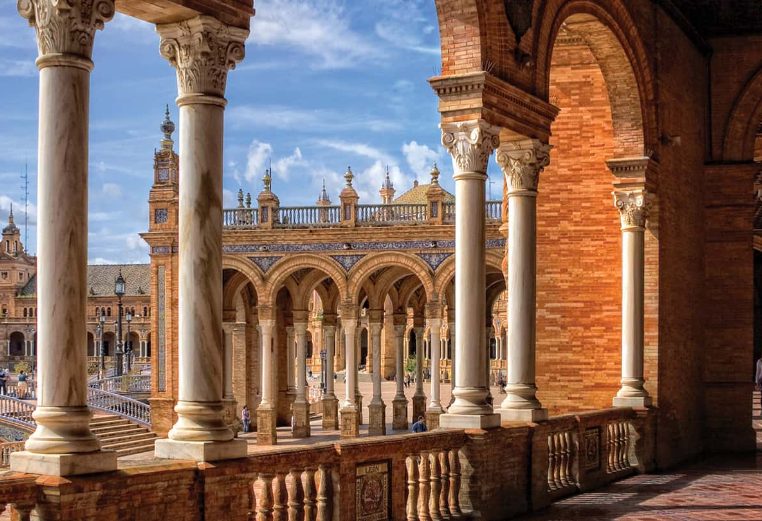 Marble columns, tall tower, and red stone architecture at the Plaza De Espana in Madrid, Spain.