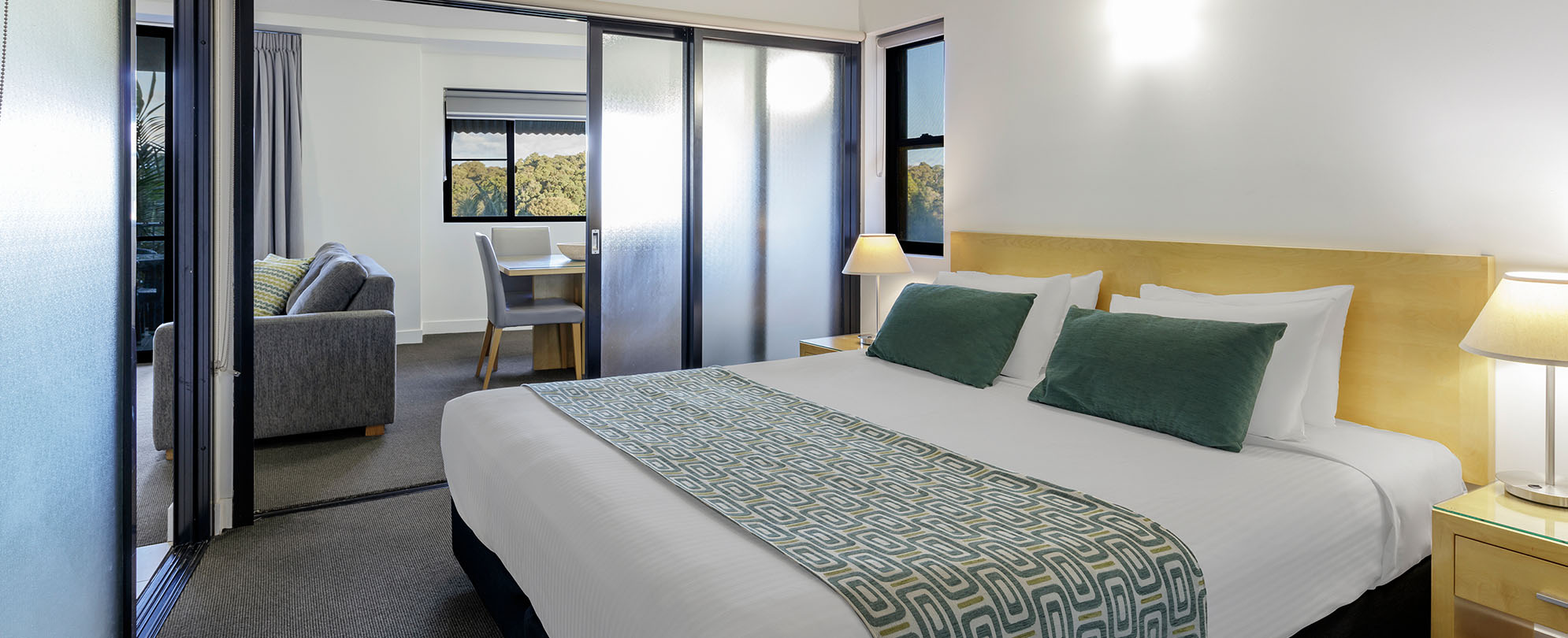 A king-sized bed in a bedroom of a 1-bedroom suite at Club Wyndham Coffs Harbor.