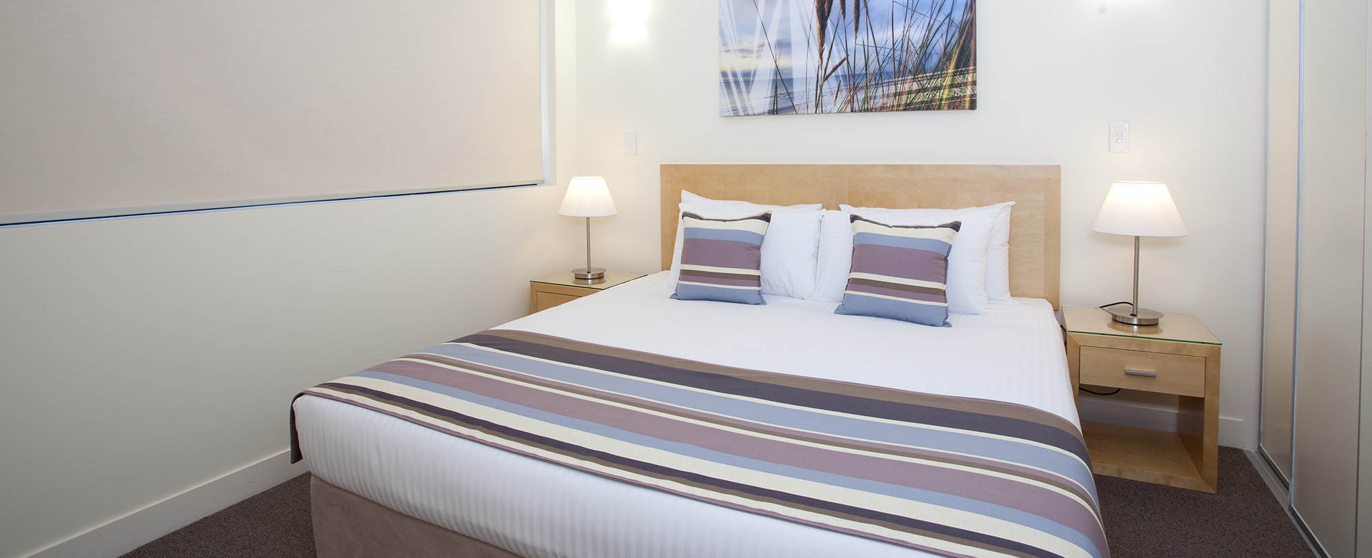 A queen-sized bed in one of the rooms in a 2-bedroom deluxe suite at Club Wyndham Coffs Harbor.