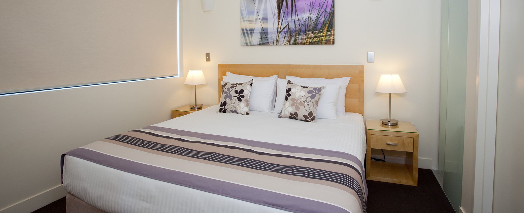 A queen-sized bed in one of the bedrooms of a 2-bedroom deluxe suite at Club Wyndham Coffs Harbor.