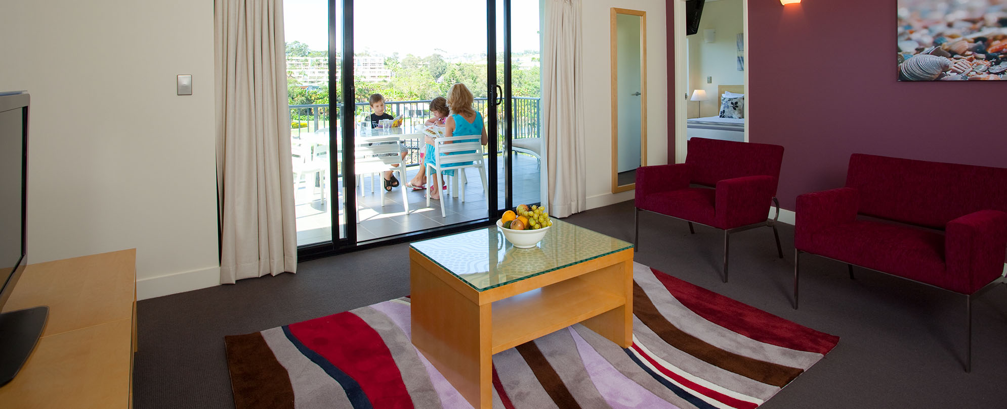 The living room and balcony of a 2-bedroom grand suite at Club Wyndham Coffs Harbor.