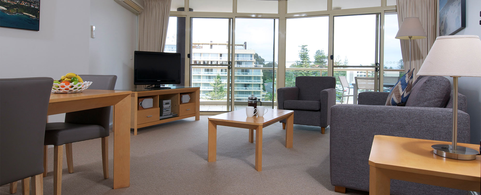 Living room of suite with floor to ceiling windows, couches and tv at Club Wyndham Port Macquarie.