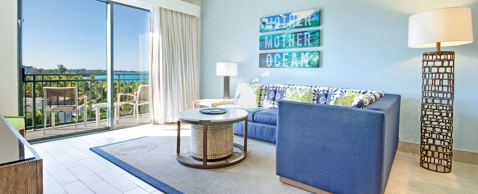 Blue sectional couch and tall lamp in the living room of a Margaritaville Vacation Club by Wyndham - Rio Mar suite.