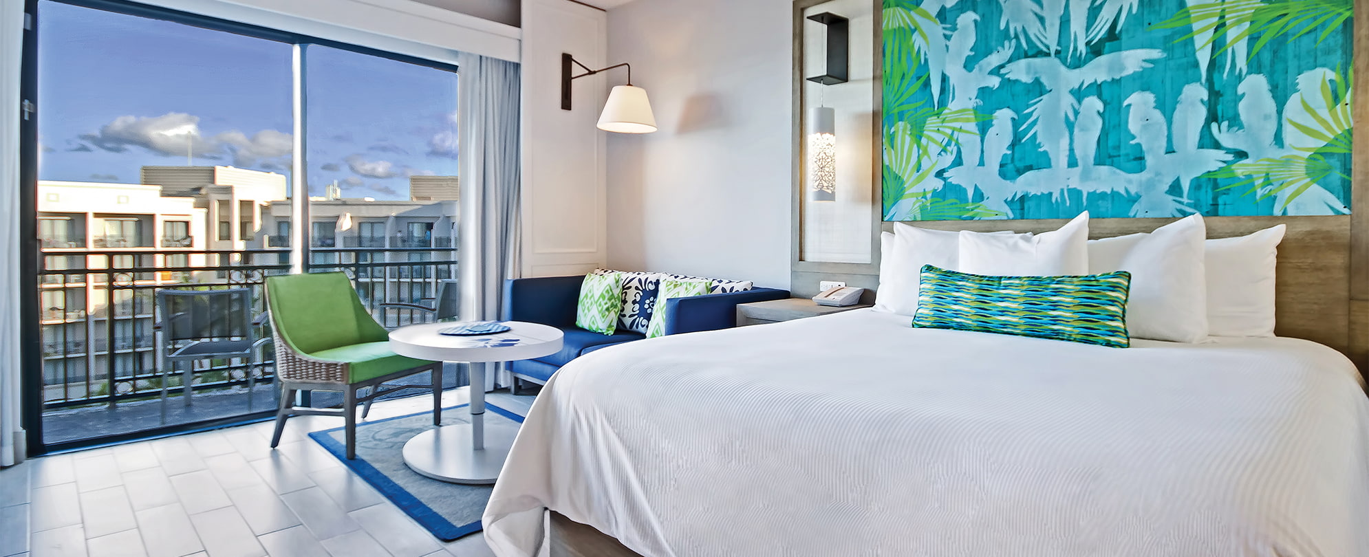 Blue couch and king bed with white linens in a studio suite at Margaritaville Vacation Club by Wyndham - Rio Mar.