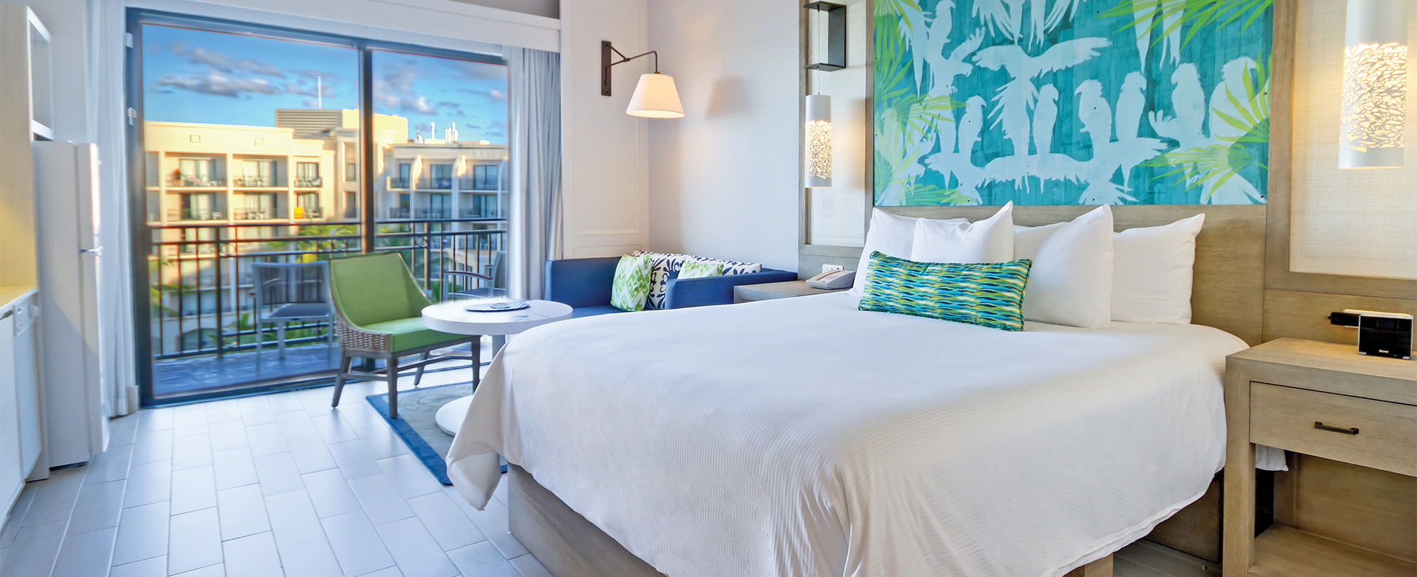 Blue couch and king bed with white linens in a studio suite at Margaritaville Vacation Club by Wyndham - Rio Mar.