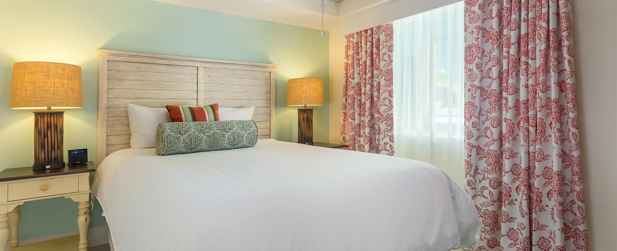 Bed with a white linens and wood headboard in a Presidential Reserve suite at Margaritaville Vacation Club resort in St. Thomas.