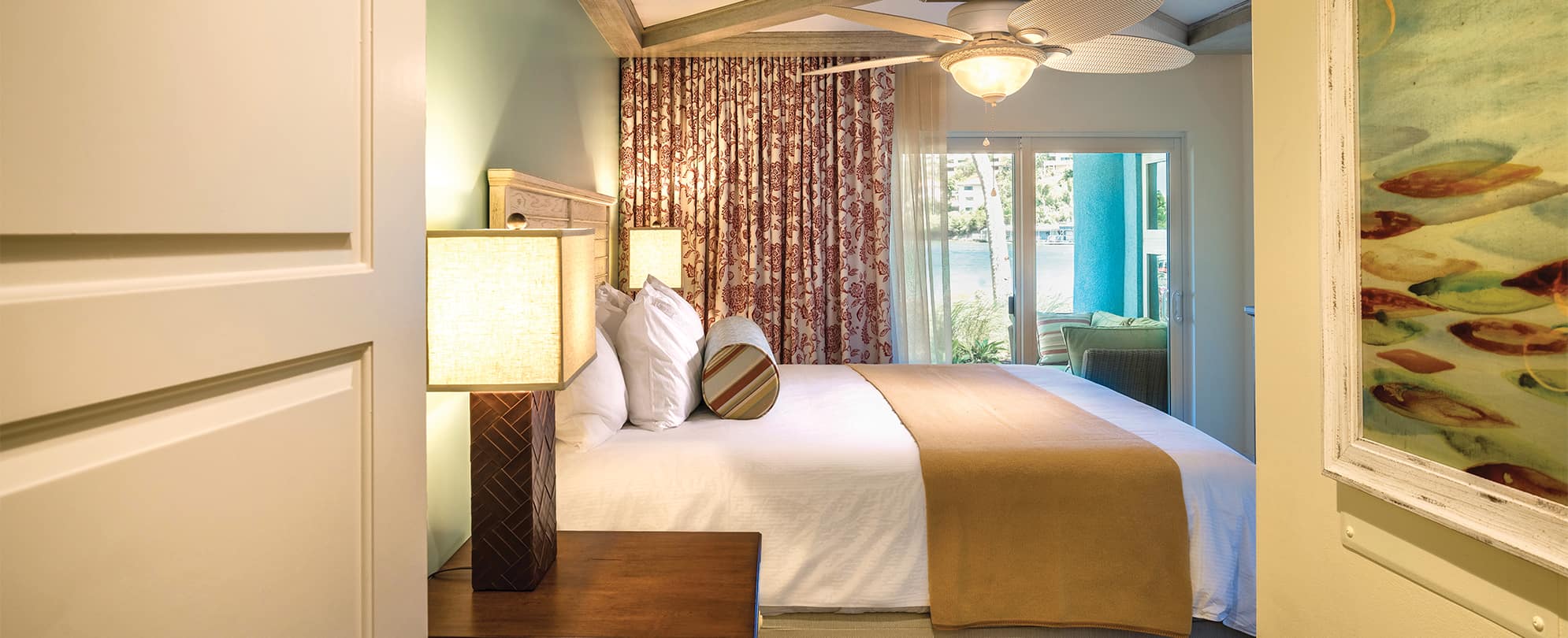 Bed with white linens and tan blanket in a Presidential Reserve suite at Margaritaville Vacation Club by Wyndham - St. Thomas.