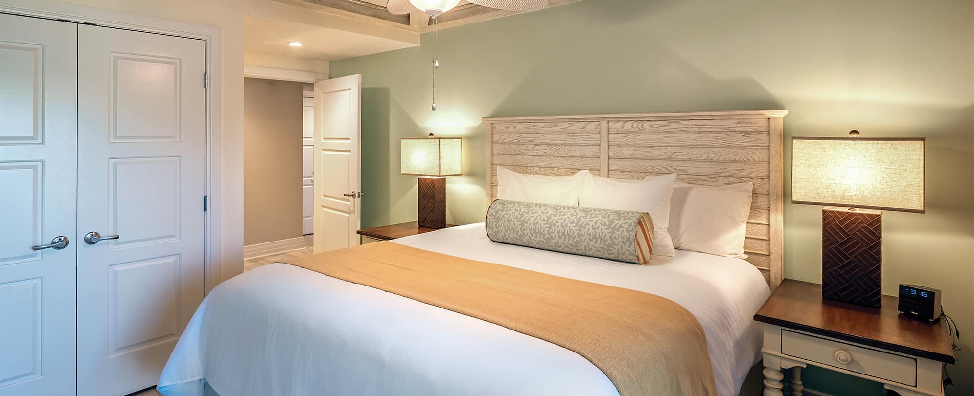 Bed with white linens and wood headboard in a Margaritaville Vacation Club Presidential Reserve suite in St. Thomas.