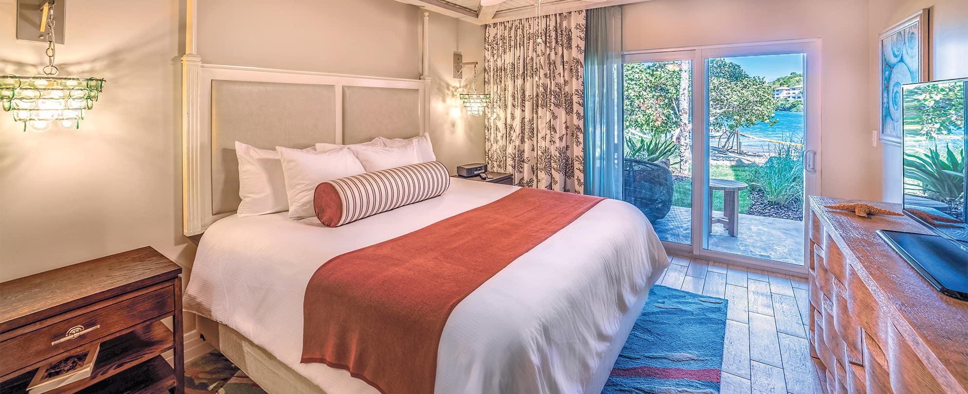 Bed with white linens and red blanket in Presidential Reserve suite at Margaritaville Vacation Club by Wyndham - St. Thomas.