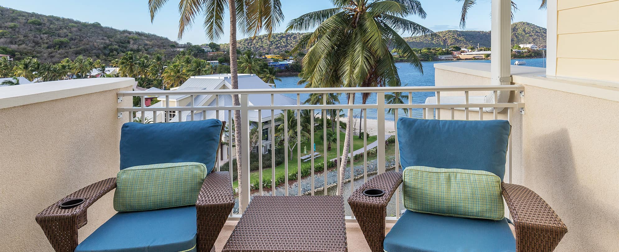 Two wicker chairs with blue cushions on an oceanfront suite balcony at Margaritaville Vacation Club by Wyndham - St. Thomas.