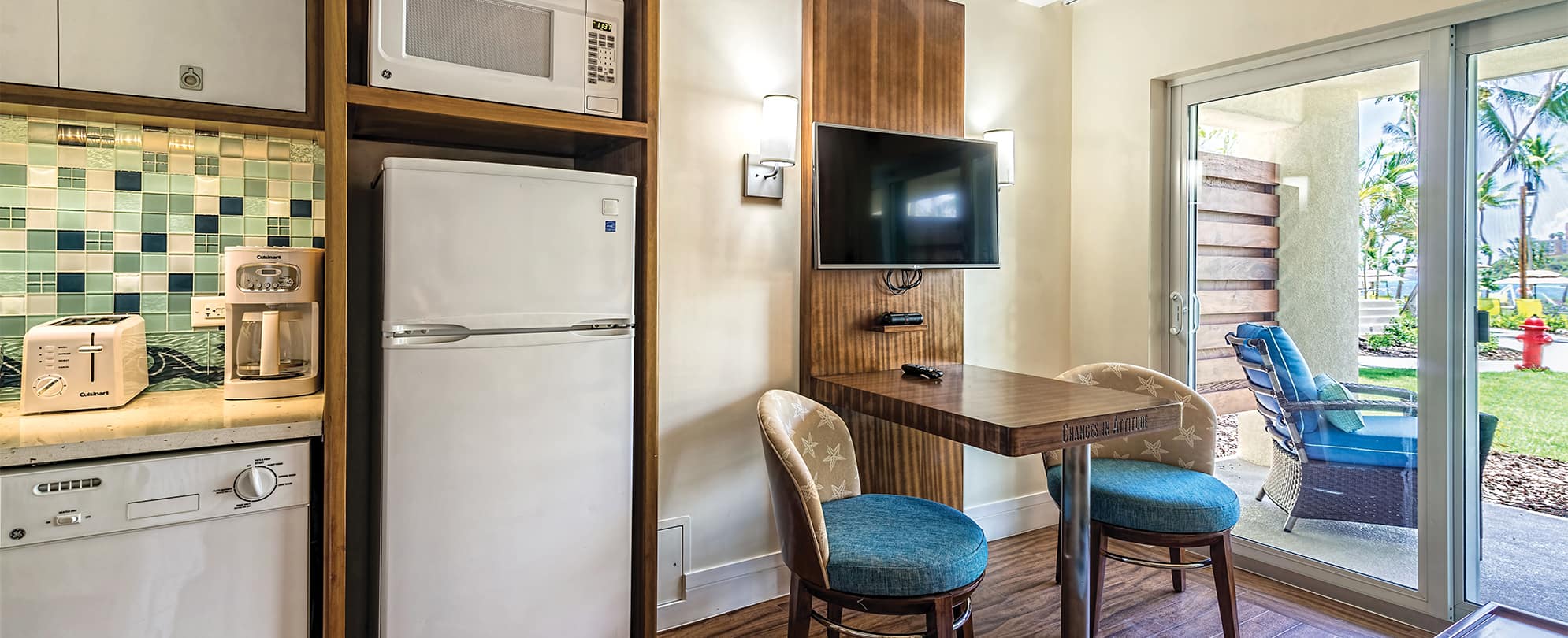 Fridge, microwave, and small table with two chairs in a studio suite at Margaritaville Vacation Club by Wyndham - St. Thomas.