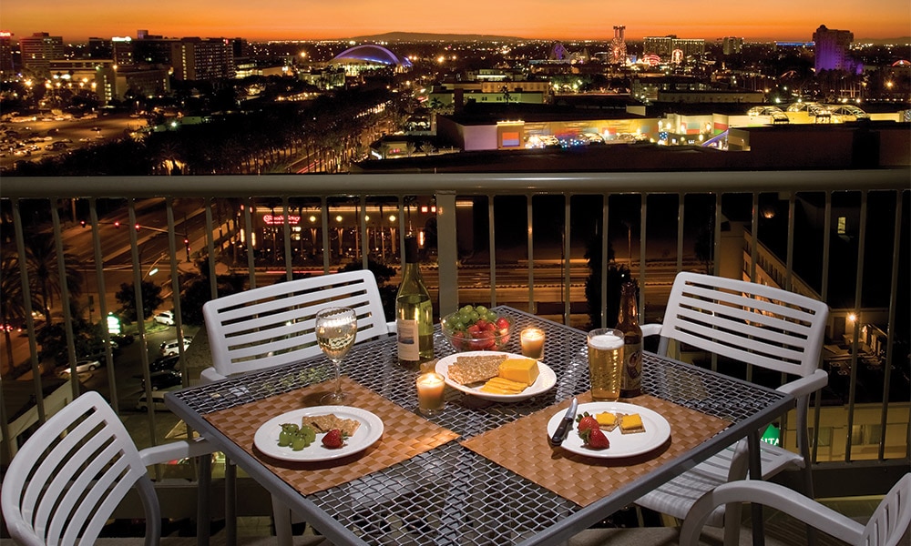 A candle-lit dinner for two, set up on the balcony of a Worldmark Anaheim Presidential Reserve suite.