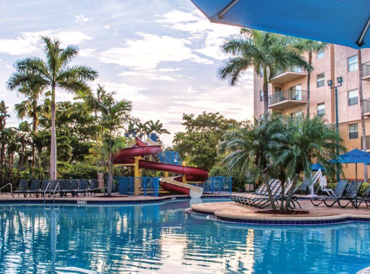 A pool surrounded by chairs and palm trees at WorldMark Palm-Air.