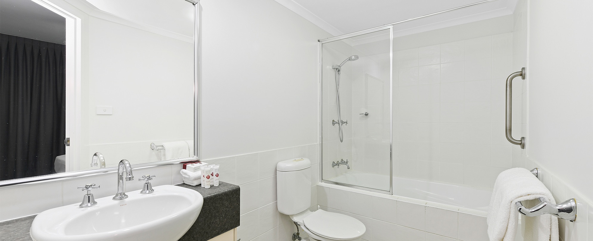 The bathroom of a standard suite at Club Wyndham Flynns Beach with a shower and tub combo, toilet, and vanity.