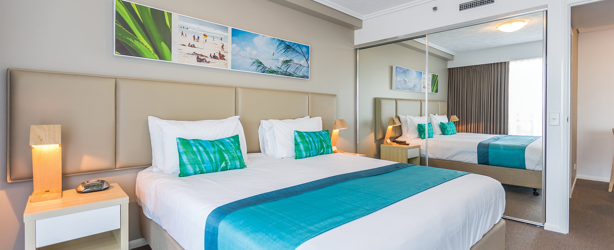 A king bed, 2 nightstands with lamps, and a mirrored closet in a Club Wyndham Kirra Beach handicap accessible suite.