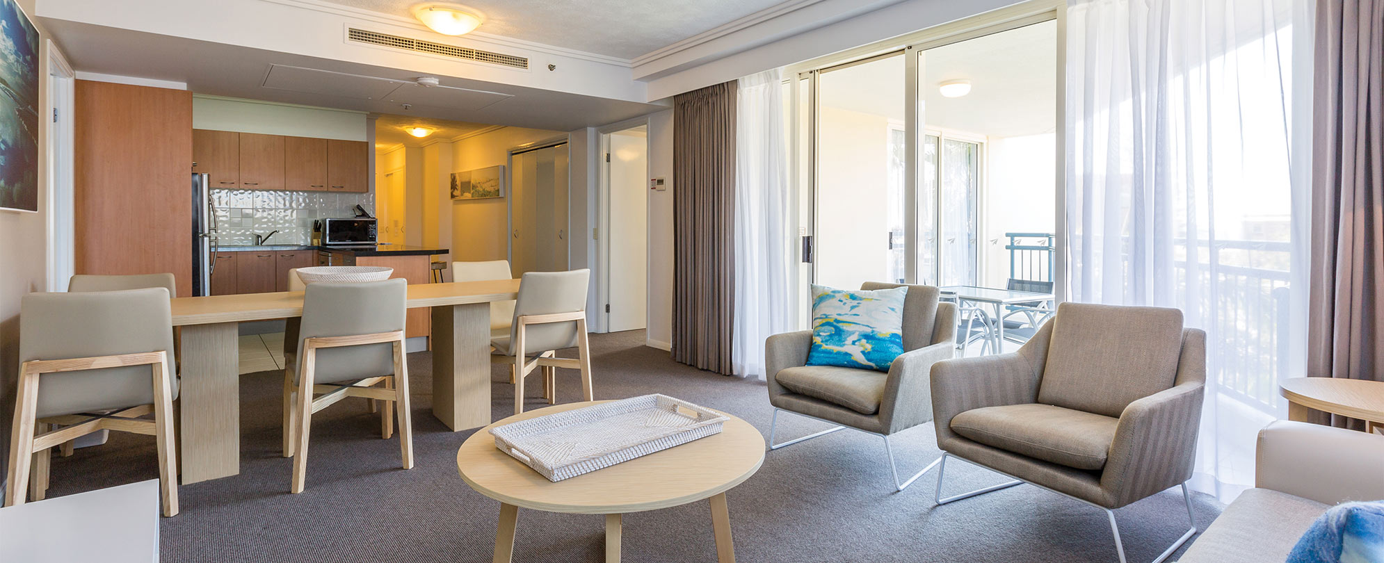 The living and dining area of a Club Wyndham Kirra Beach standard suite with a dining table, coffee table, and chairs.