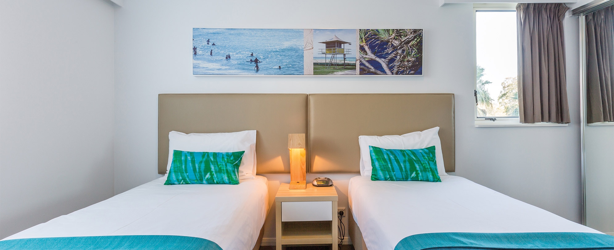 A bedroom with two twin beds and a nightstand with a lamp in a Club Wyndham Kirra Beach standard suite.