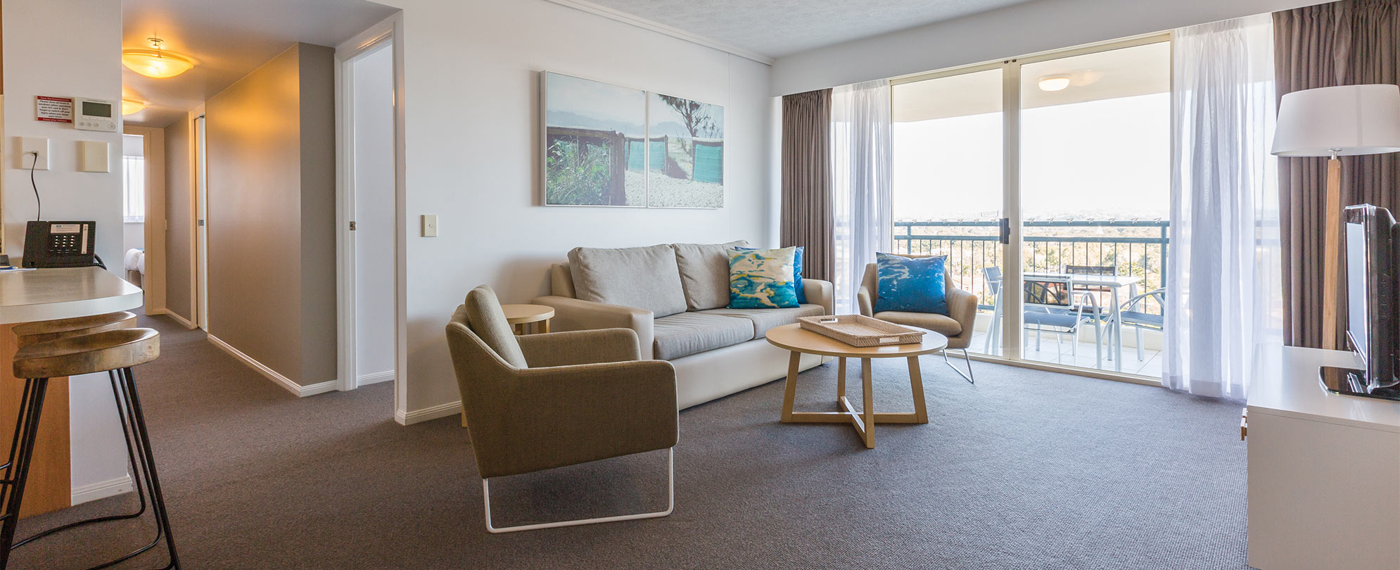 The living area of a Club Wyndham Kirra Beach standard suite with a hallway leading to bedrooms and bathrooms.
