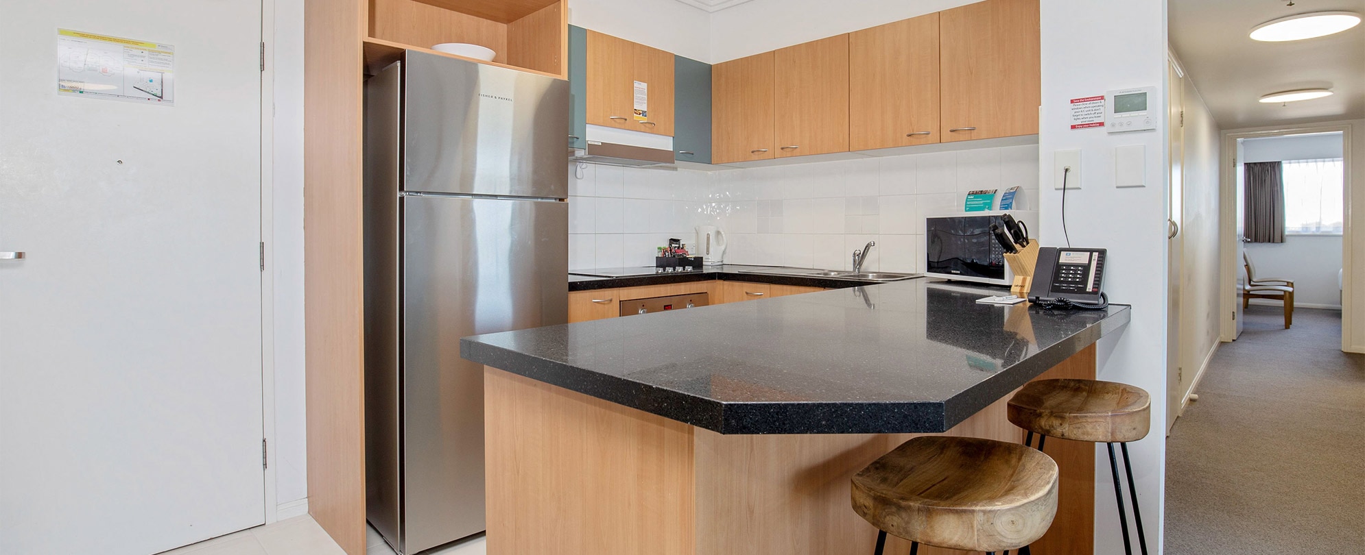 The kitchen of a Club Wyndham Kirra Beach standard suite with a full fridge, microwave, stove, countertop bar, and sink.