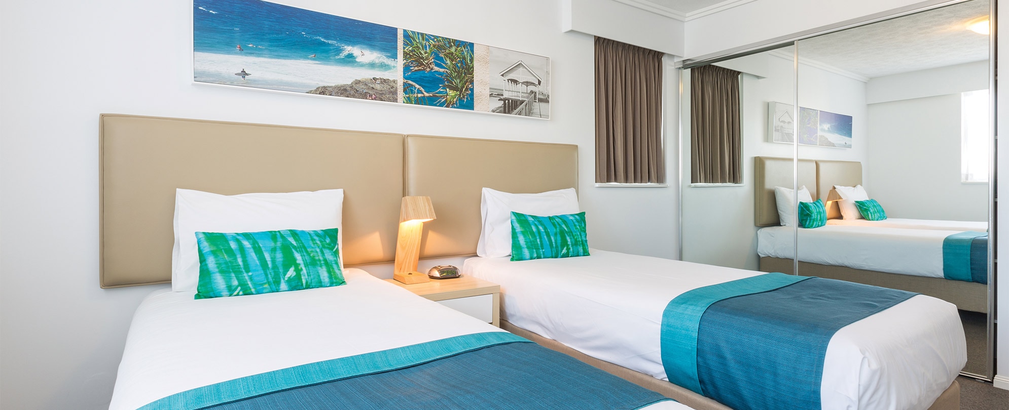 A bedroom with 2 twin beds and a nightstand with a lamp in a Club Wyndham Kirra Beach standard suite.