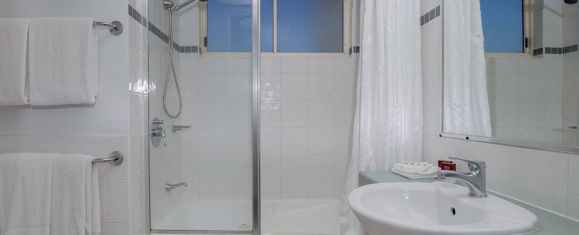 The bathroom of a Club Wyndham Kirra Beach standard suite with a shower/tub combo, towels, sink, and mirror.