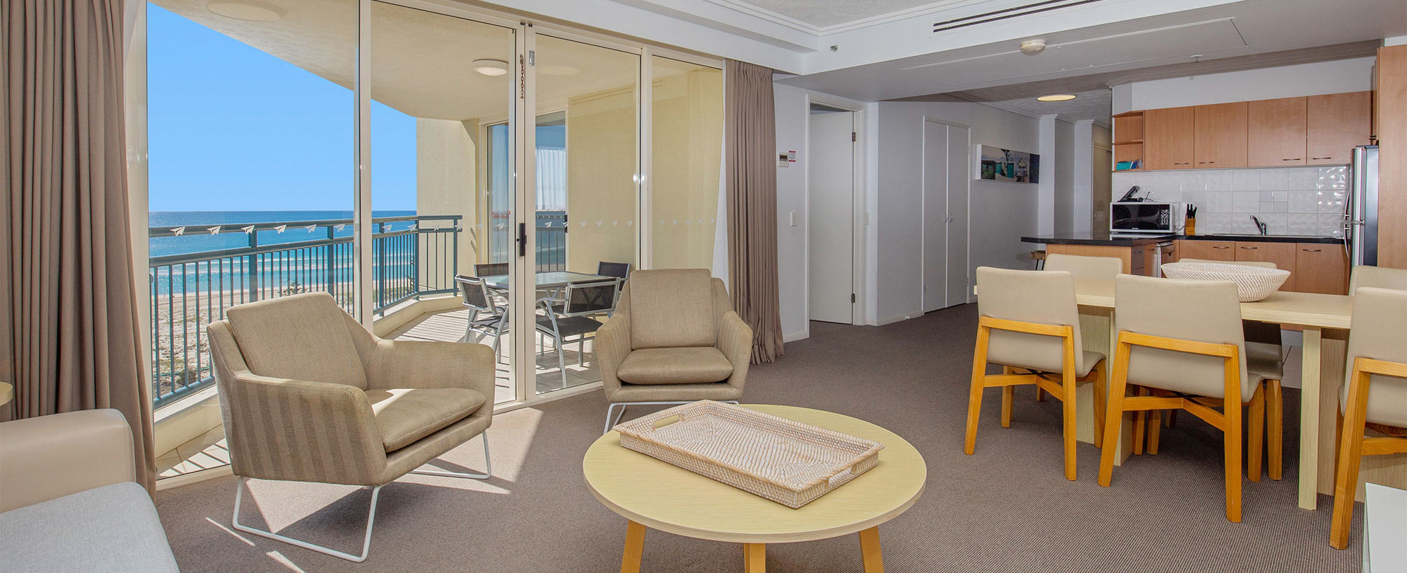 The living area, kitchen, and dining table in a Club Wyndham Kirra Beach ocean view suite.