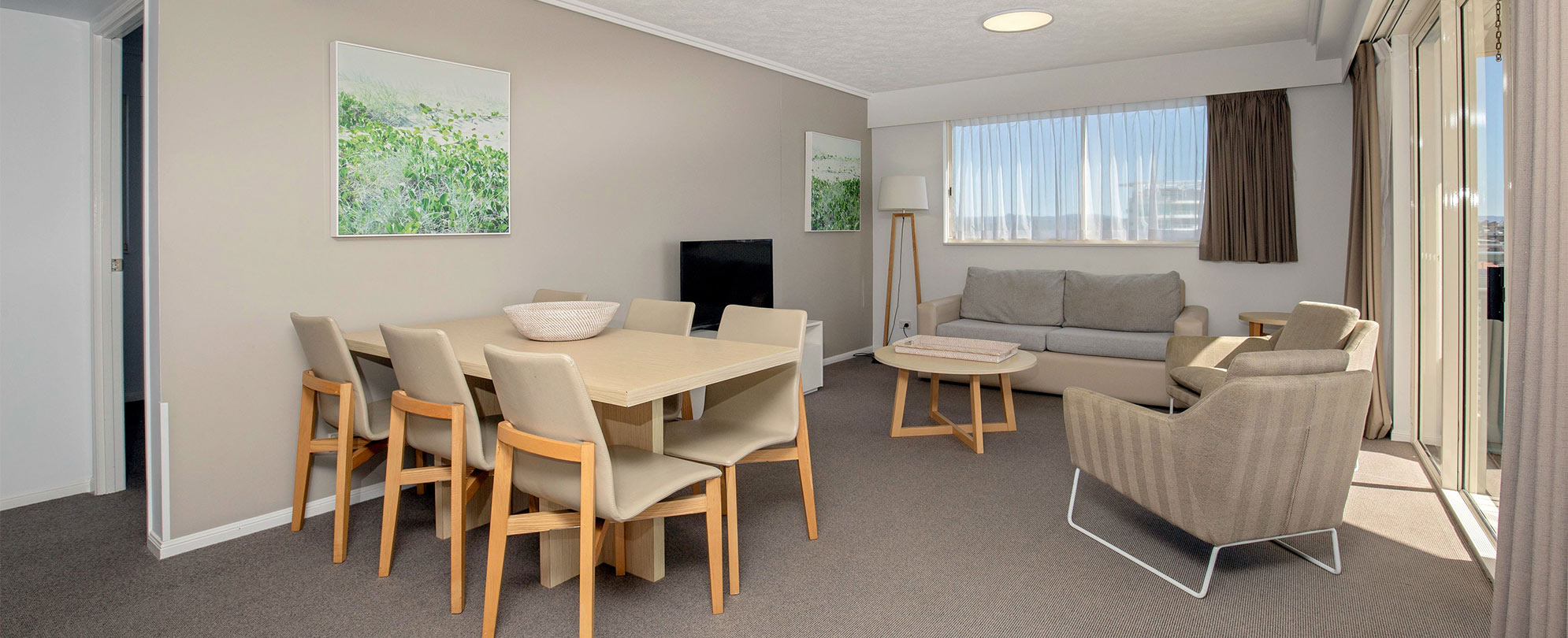 The living area and dining table with 6 chairs in a Club Wyndham Kirra Beach standard suite.