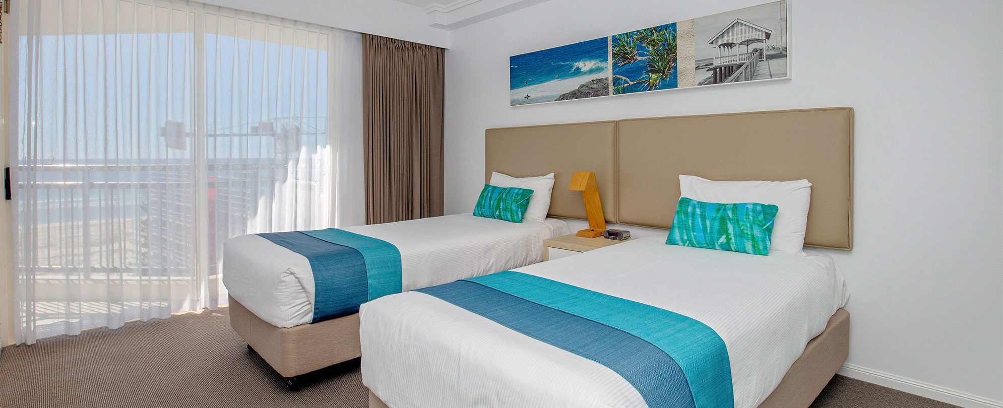 A bedroom with 2 twin beds and a nightstand with a lamp in a Club Wyndham Kirra Beach standard suite.