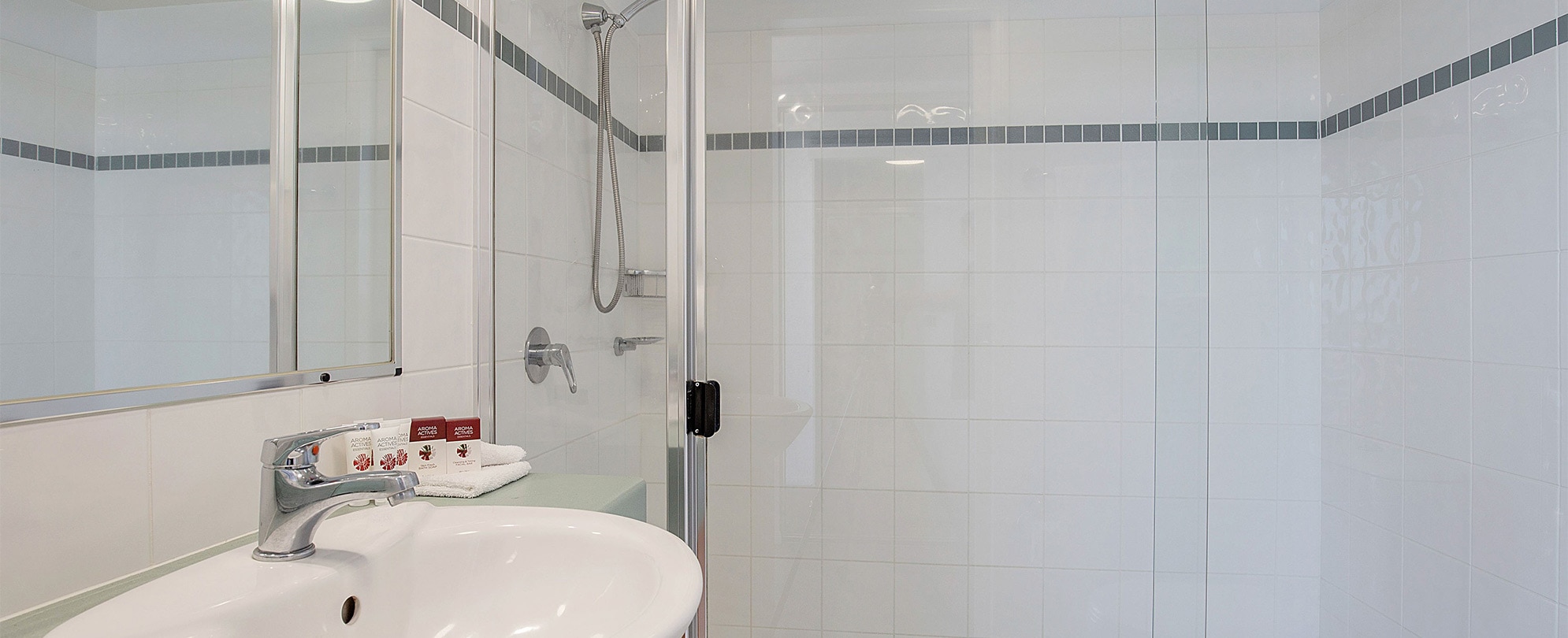 A bathroom with a glass shower and vanity sink in a Club Wyndham Kirra Beach standard suite.