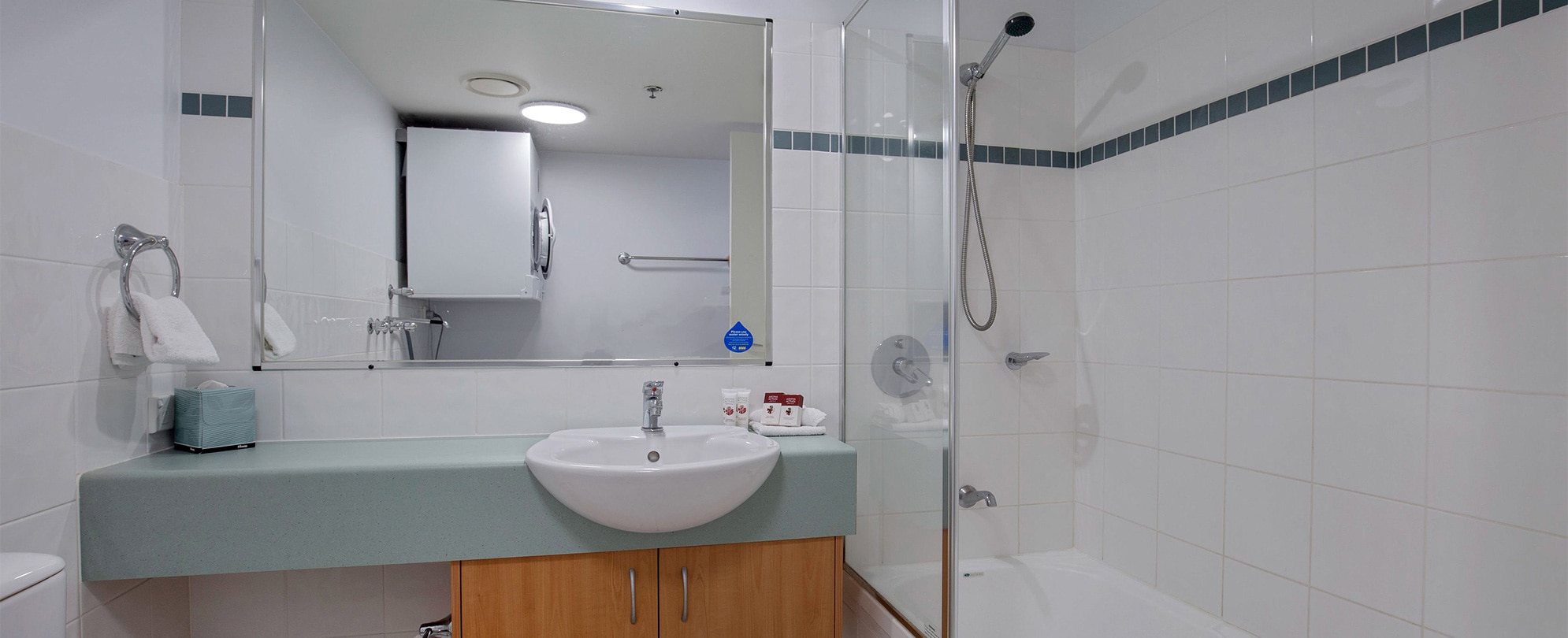A bathroom with a shower/tub combo, vanity sink, and mirror in a Club Wyndham Kirra Beach standard suite.