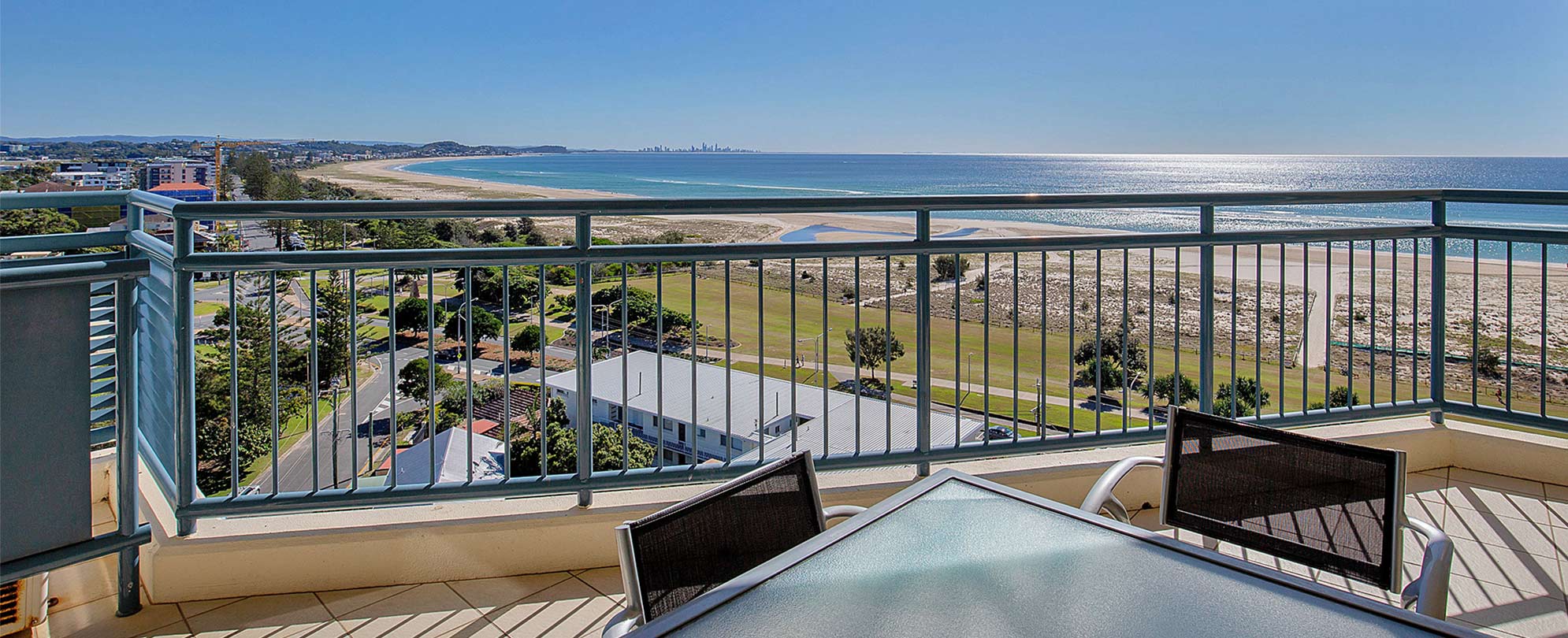 A balcony with a table and chairs and a view of the ocean at a Club Wyndham Kirra Beach standard suite.