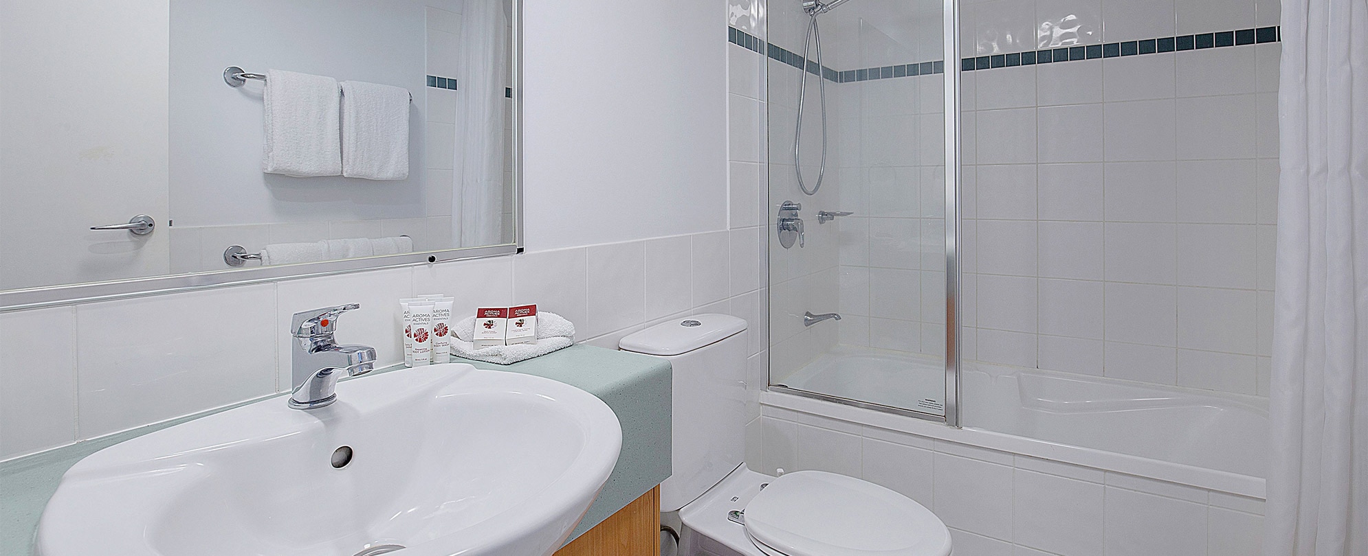 A bathroom with a shower/tub combo, toilet, vanity sink, and mirror in a Club Wyndham Kirra Beach standard suite.