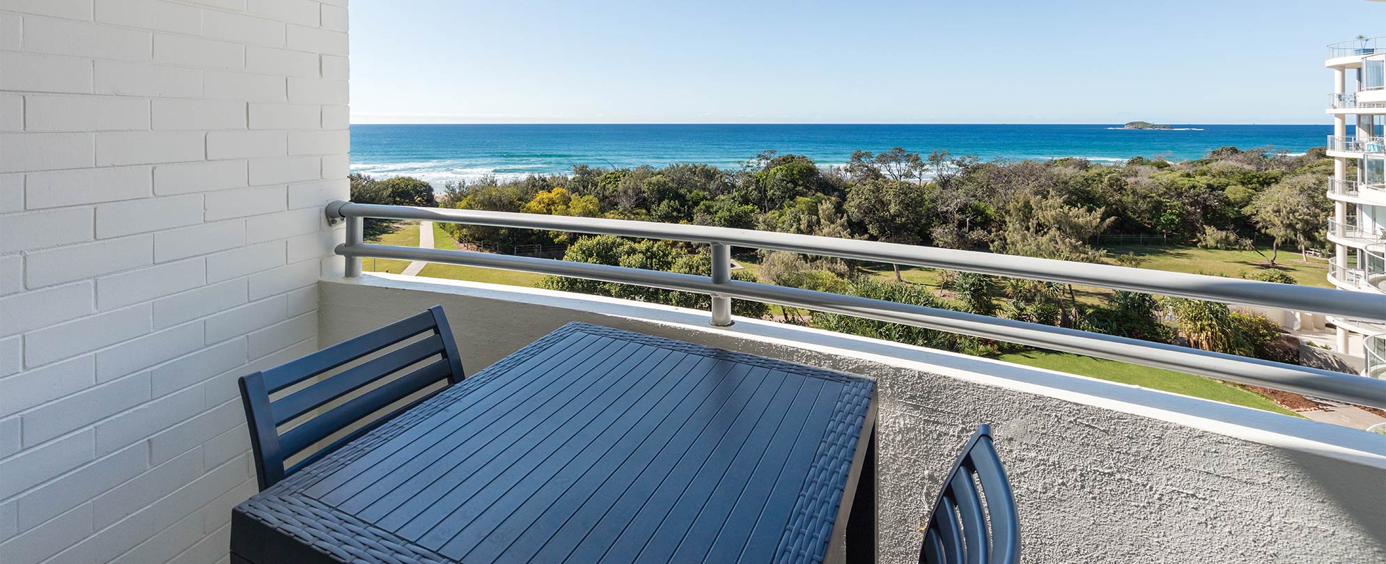 A balcony with a table and 2 chairs with a view of the ocean at a Club Wyndham Marcoola Beach suite.