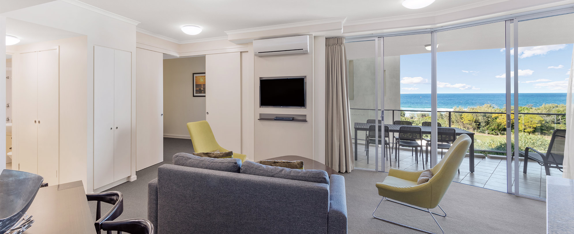 The living area of a Club Wyndham Marcoola Beach standard suite with a sliding glass door leading to a balcony.