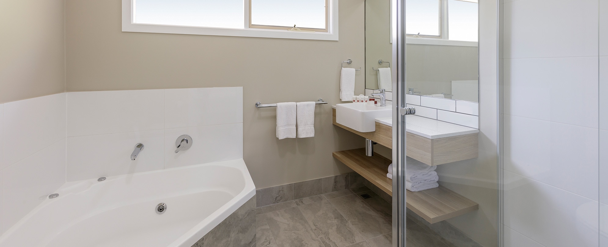 A soaking tub, glass shower, and a vanity sink and mirror in the bathroom of a Club Wyndham Phillip Island studio suite.