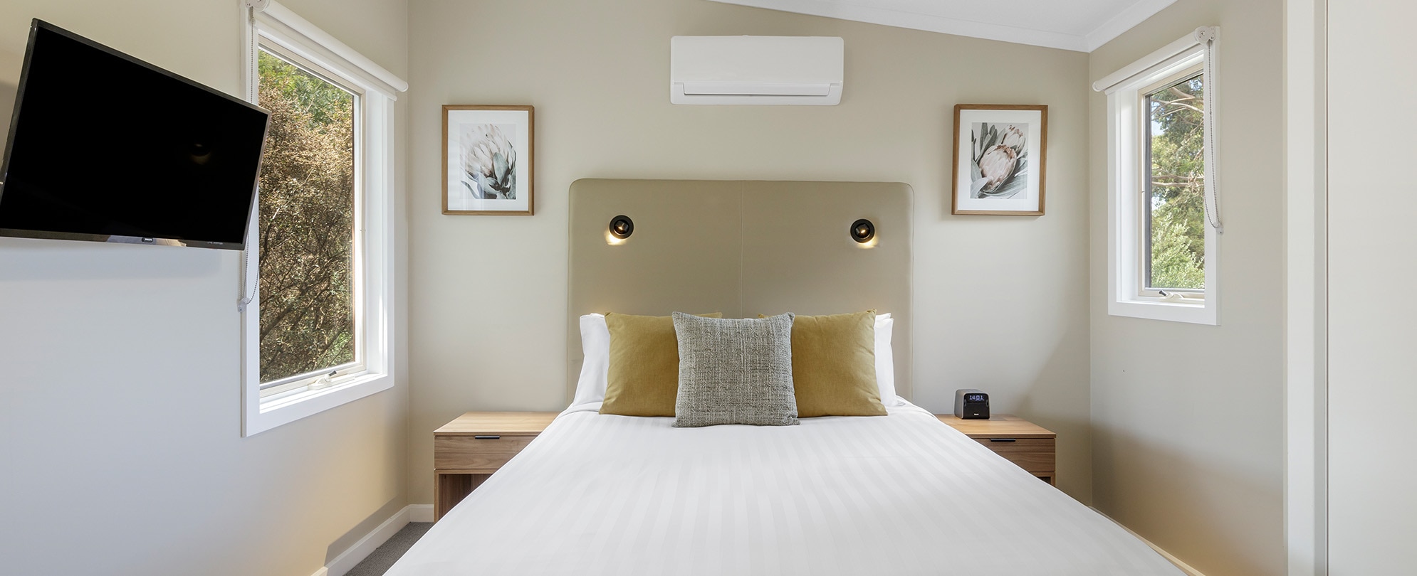 A bed with a headboard, 2 nightstands, flat screen TV in a Club Wyndham Phillip Island 3-bedroom suite.