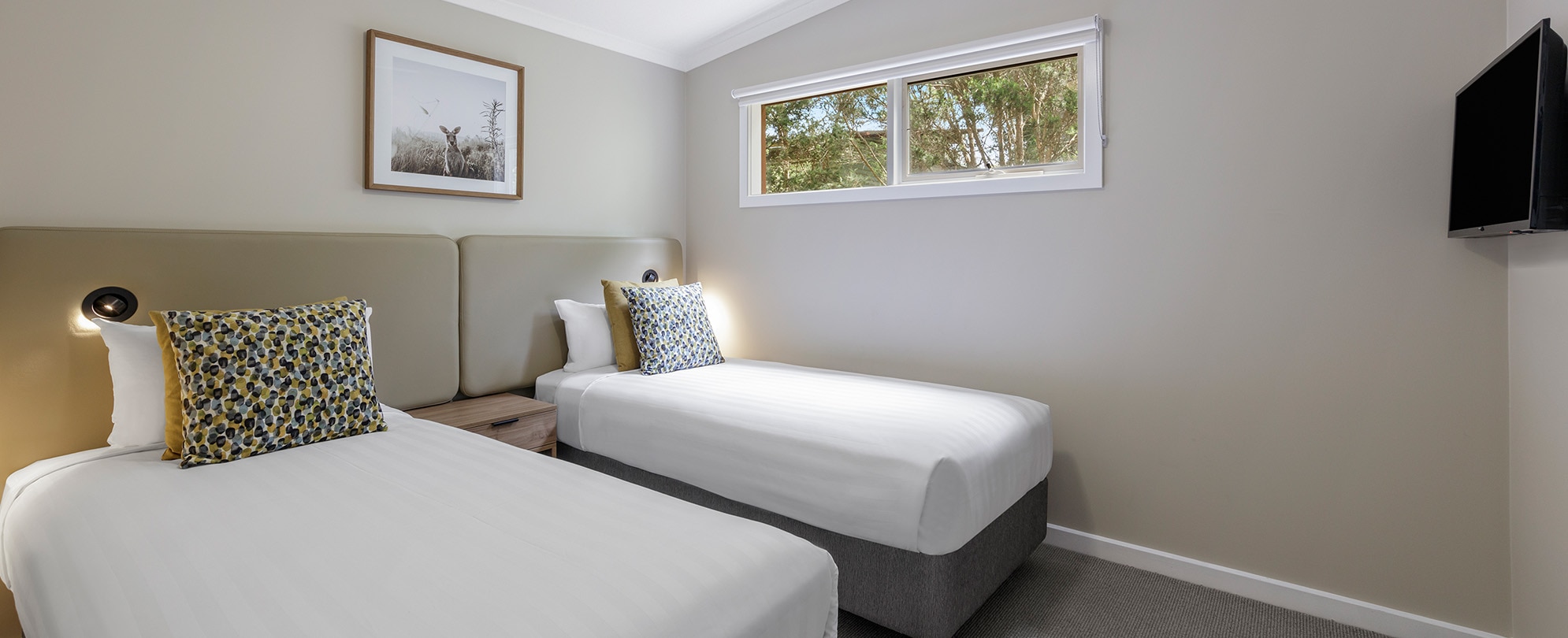 A bedroom with 2 twin beds and nightstand in a Club Wyndham Phillip Island 3-bedroom suite.