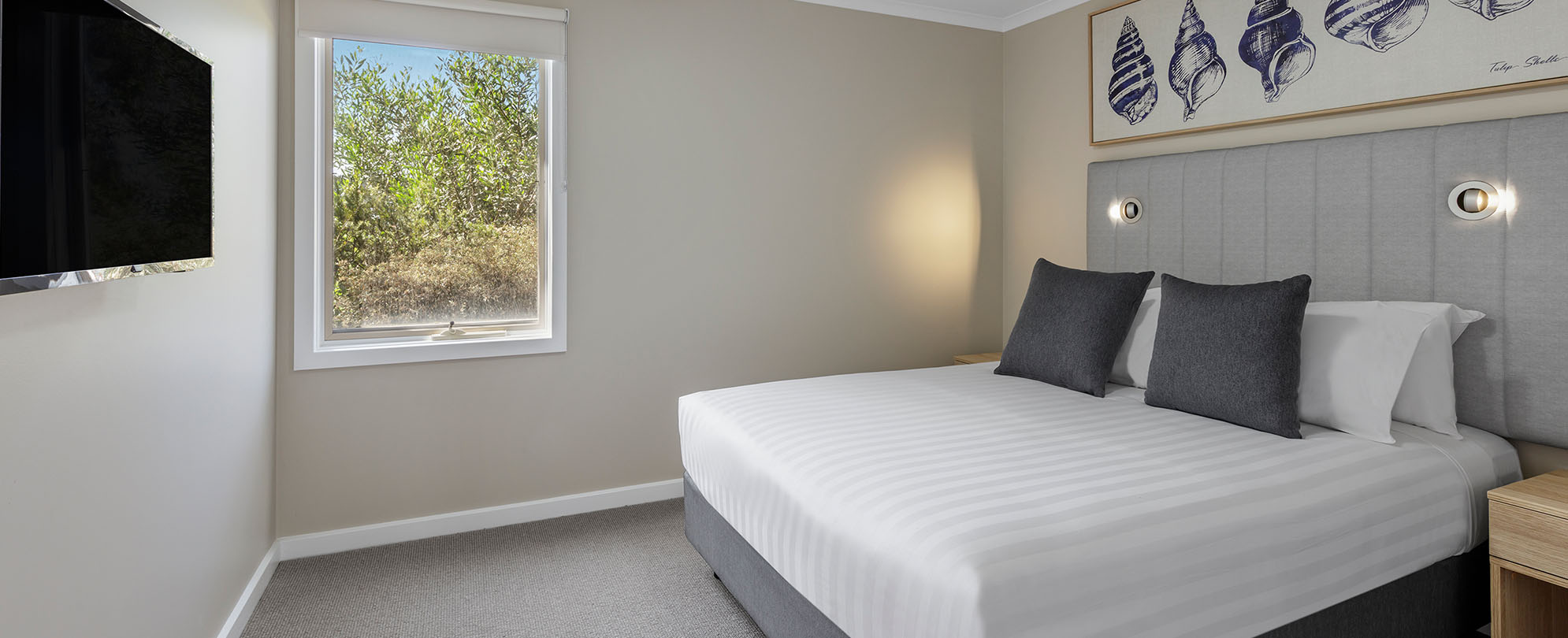 A bedroom with a king bed with 2 nightstands, a flat screen tv at a Club Wyndham Phillip Island 2-bedroom suite.