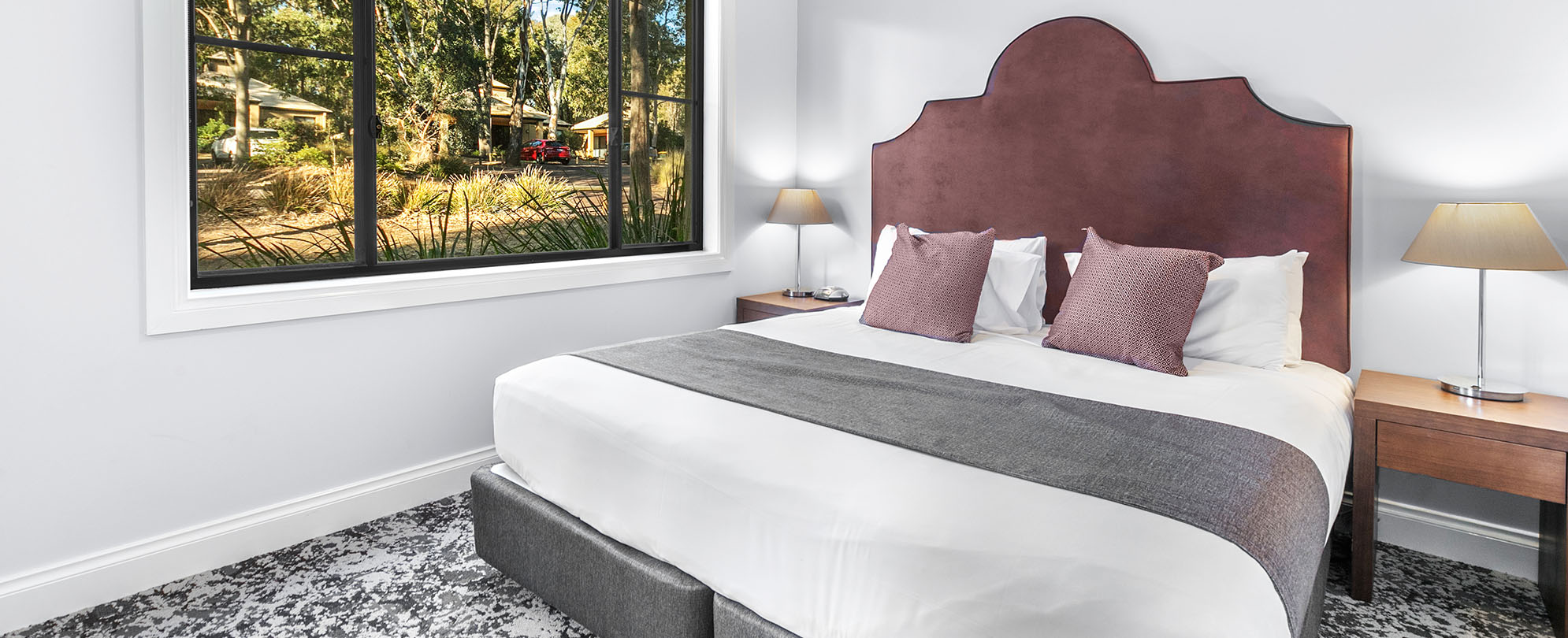 A bed with a headboard, and 2 side tables with lamps in a 1-bedroom suite at Club Wyndham Pokolbin Hill.