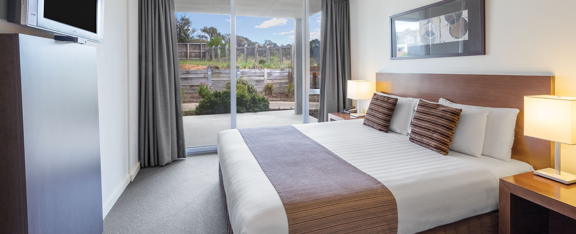 A king-sized bed, neatly made inside a 1-bedroom suite at Club Wyndham Torquay.